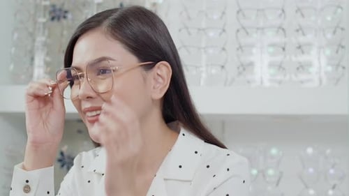 Young female customer choosing glasses in optical center