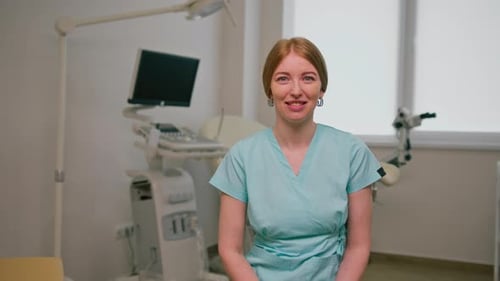 smiling doctor gynecologist sits in gynecological office near ultrasound machine and gynecological
