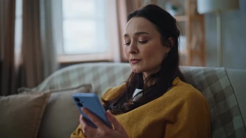 Serious Brunette Receiving Message Cellphone Sitting Sofa Closeup Upset Woman