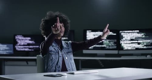 Imágenes en 4K de una joven programadora dibujando en una pantalla transparente mientras trabaja hasta altas horas de la noche
