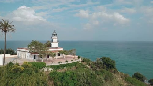 Wide aerial shot of lighthouse on the coast above the ocean in Catalonia, Spain
