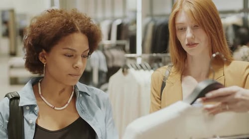 Two Diverse Girlfriends Shopping at Clothing Designer Showroom
