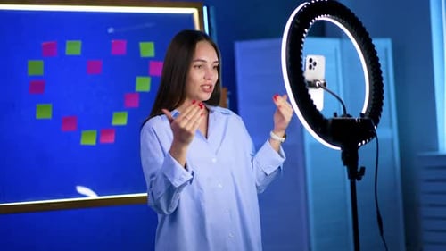 Smiling young woman speaks to camera using ring light