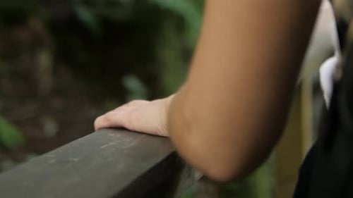 Slow motion of a woman going down on the steps and putting her hand on the wood handrail.