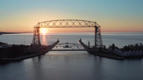 Vista aérea con un dron rastreando la puesta de sol a través de la estructura metálica de un puente elevador en Duluth, Minnesota: tienda de drones