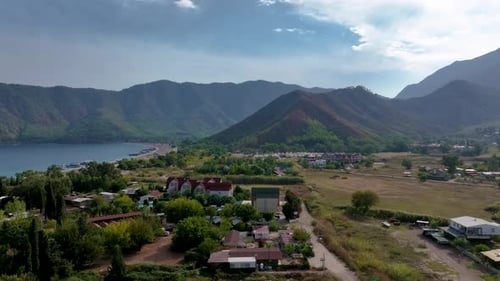 Camera Panning Over a Green Valley with Buildings and Mountains in the Background The Shot Shows a