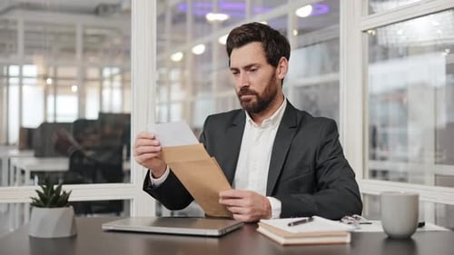 Happy Businessman Receives Good News in Letter at Office Desk