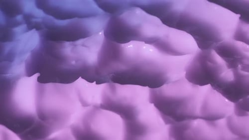 Close Up Shot of Violet Pink Cream Background Face or Body Cream Fluid Texture with Peaks Rotating