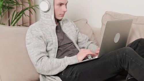 Young Adult Using Laptop and Headphones at Home