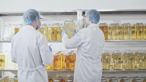 Deux travailleurs professionnels du labolatorium vérifient la qualité du stockage du liquide chimique jaune dans