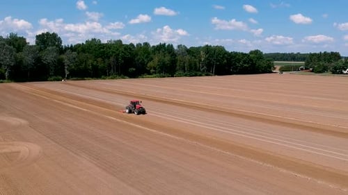Tractor at work, prepares the field for planting seeds. Aerial view.