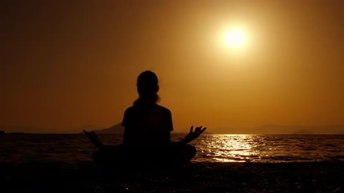 Woman Meditating at Sunrise on Beach