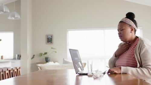 Woman at Laptop Holding Throat with Cough
