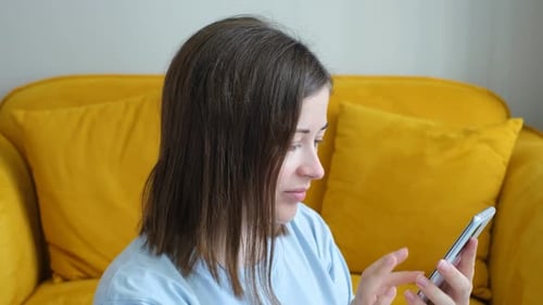 Woman Using Smartphone While Sitting on Couch Indoors
