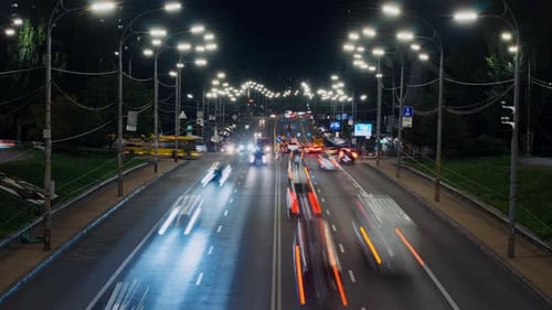Time Lapse of Traffic in City with Tall Buildings and Lanterns at Night