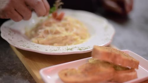 Chef sou-chef cook decorating carbonara spaghetti with fresh parsley at a local restaurant diner caf