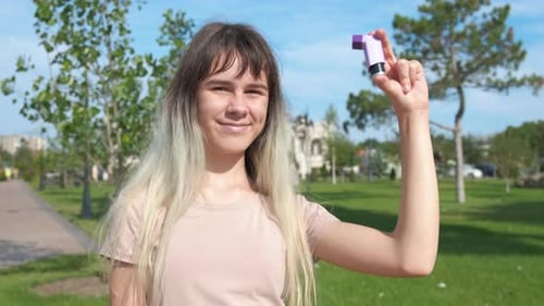 Young Woman Presenting Asthma Inhaler in Park