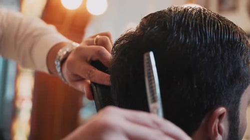 Hairdresser cutting hair of a man with scissors in a barber shop. Shot in slowmotion at 50%