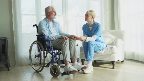 Elderly Man and Young Caregiver Holding Hands