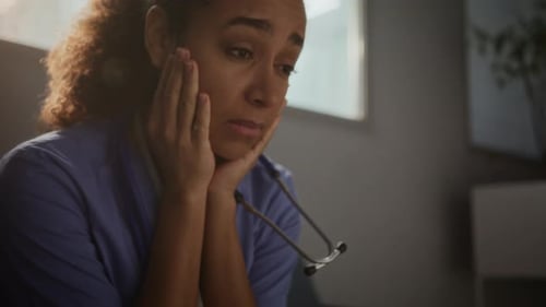 Woman Sits Displaying Distress with Face Resting in Hands