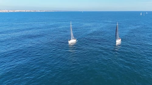 A small sailboat is navigating through the vast open ocean, surrounded by nothing but water. The sai