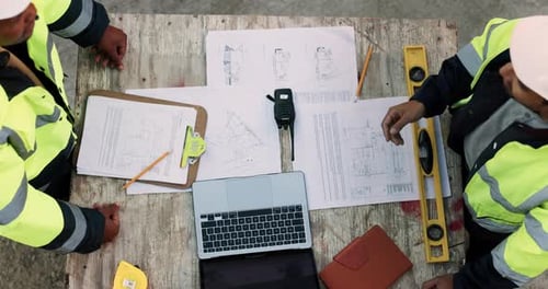 Blueprint, laptop and construction managers with handshake on site for industrial partnership