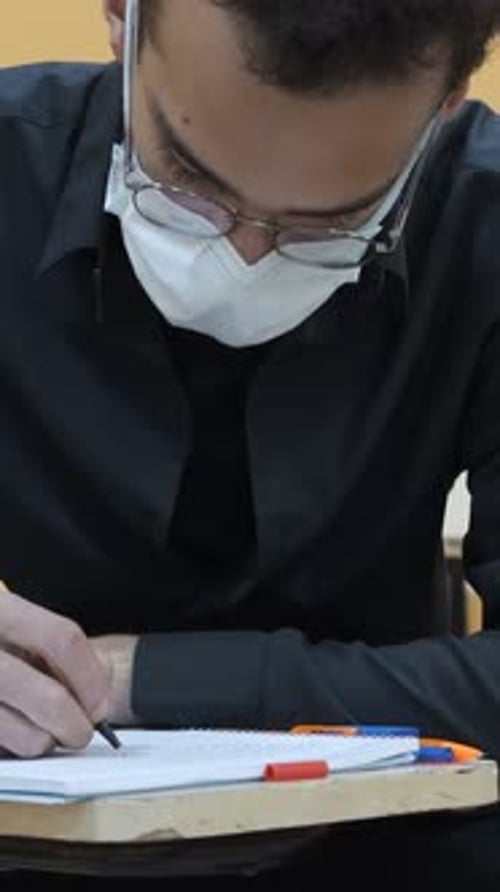 Young Adult Writing with Face Mask and Glasses