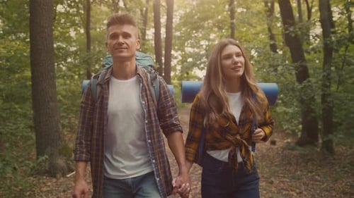 Couple Hiking Through a Forest on a Sunny Day While Holding Hands