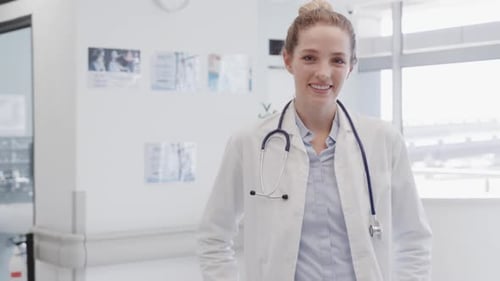 Portrait of happy female doctor with stethoscope smiling in hospital, in slow motion, copy space