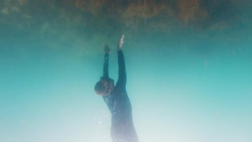 Man Dives in the Murky Sea and Swims Underwater Over the Bottom with Weed