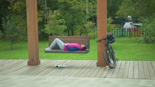 Woman Relaxing on a Swing in the Park