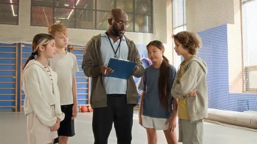 Black Man as Coach with Children in Gym and Giving Instructions