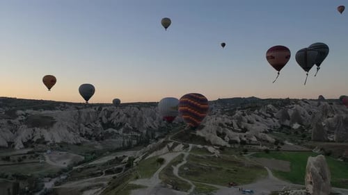 Hot Air Balloons Fly Over Desert Landscape at Sunrise