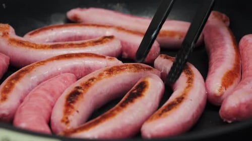 Meat Sausage on a Pan Grill Closeup Traditional Fast Food Flipping Sausages in a Frying Pan