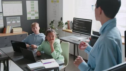 Teacher Interacting with her Students During Programming Lesson in School