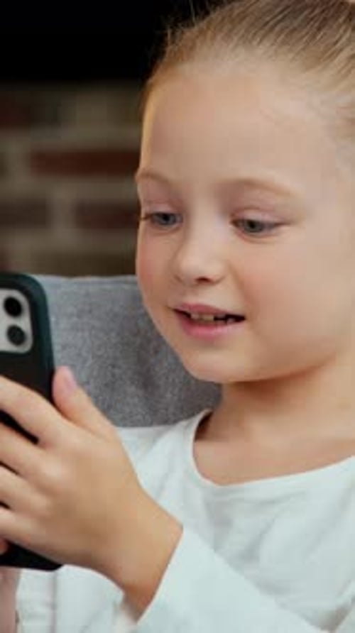 Blonde Girl Engrossed in Mobile Phone Indoors
