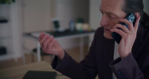 Angry Businessman Talking on Smartphone in Office