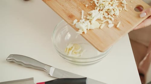 Woman Pushing Chopped Eggs into Clear Glass Bowl