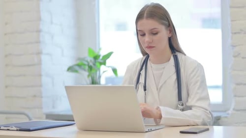 Busy Female Doctor Typing on Laptop in Clinic