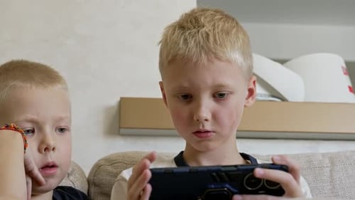 Young Boys Concentrating on Smartphone at Home