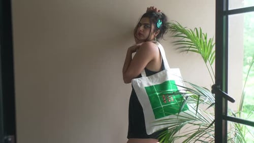 Mujer de moda posando con una bolsa de mano ecológica en un entorno elegante