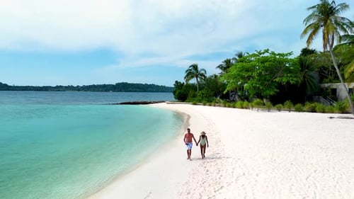 Couple Walking Along the Pristine White Sandy Shores of Koh Kham Island in Thailand