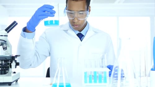 Research Scientist Pouring Chemical in Beaker for Reaction in Laboratory
