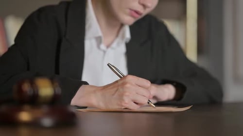 Close Up of Female Judge Writing a Legal Verdict in Court