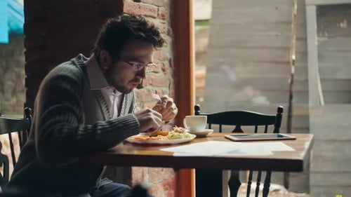 Young Businessman Working with a Tablet While is Eating a Restaurant