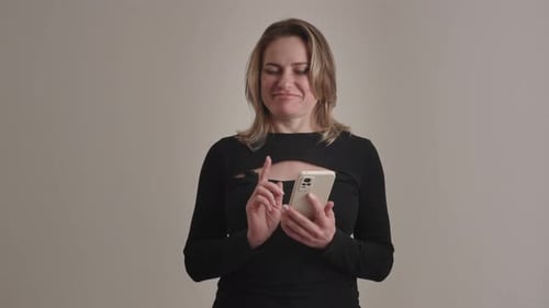 A Woman with a Black Outfit is Smiling While Using a Smartphone with an Isolated Background