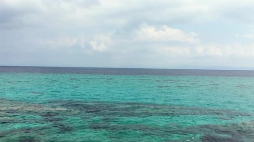 Mar. Agua clara. Día de verano. Costa y cielo azul con nubes.