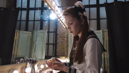 Young Woman Applies Makeup at Vanity Mirror