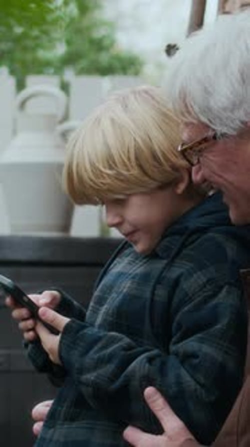Grandson and Grandfather Look at Phone Together