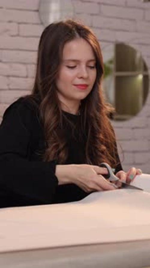 Woman Cutting Paper with Scissors at Home